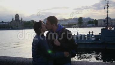 一对相爱的夫妇站在城市里一条河附近的海滩上亲吻。 慢动作。 <strong>1920</strong>x1080。 全高清